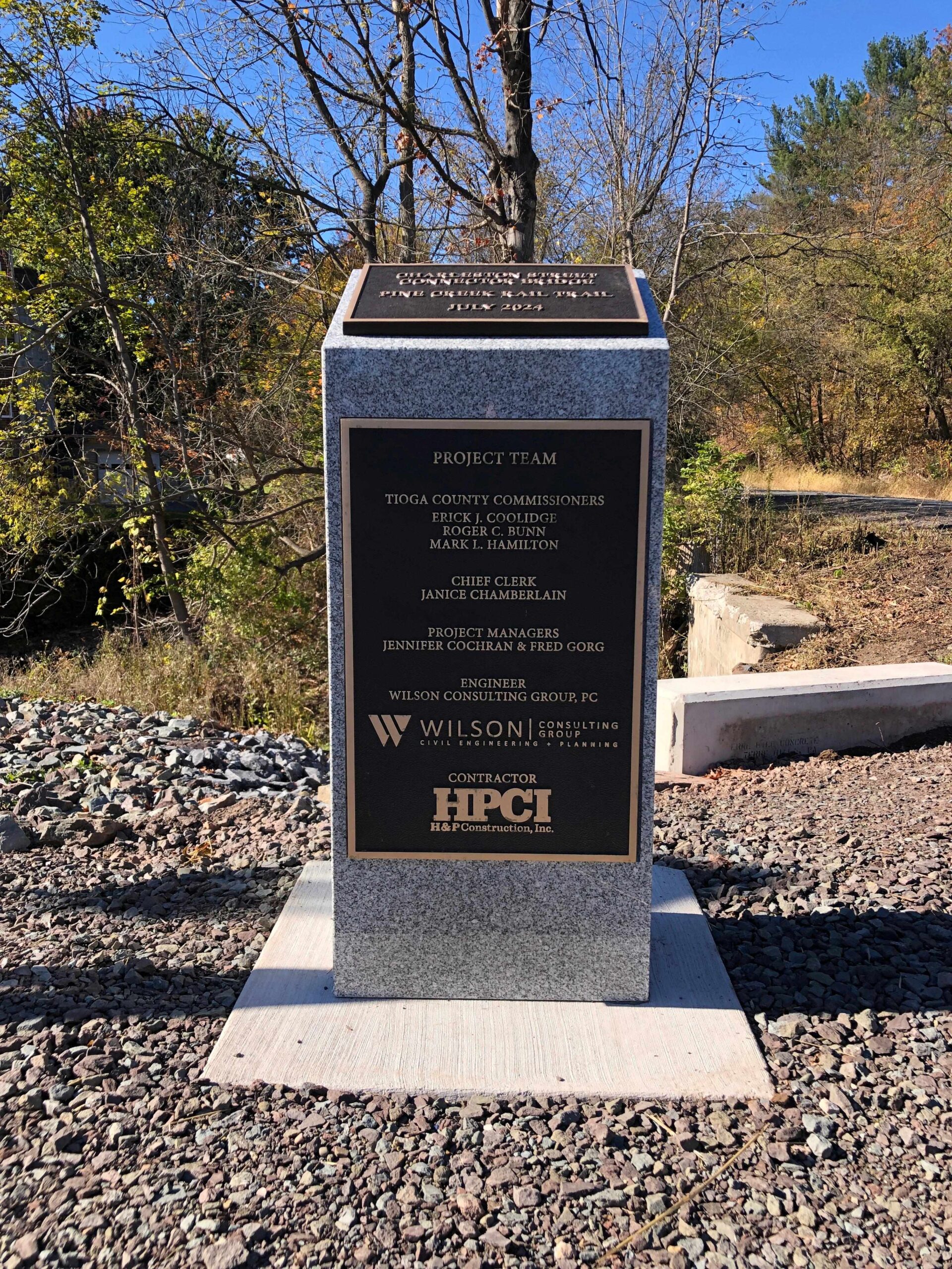 Stone monument with bronze plaques in a wooded area.