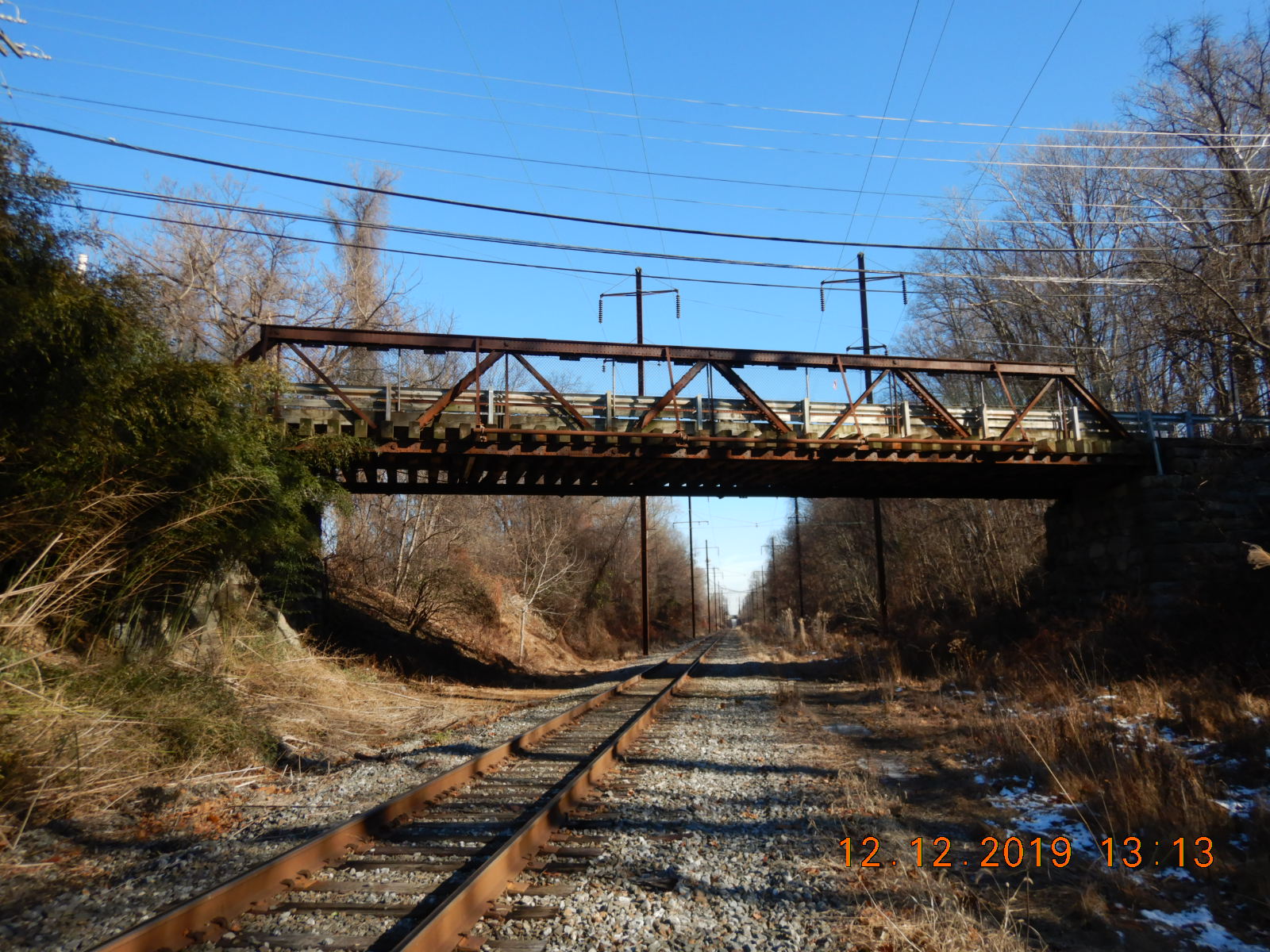 Rusty metal bridge over railroad tracks.