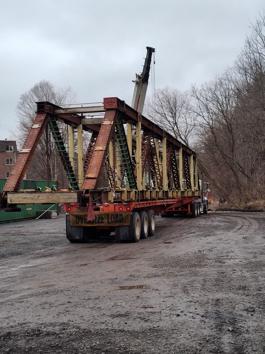 Metal bridge being driven away on a truck bed.