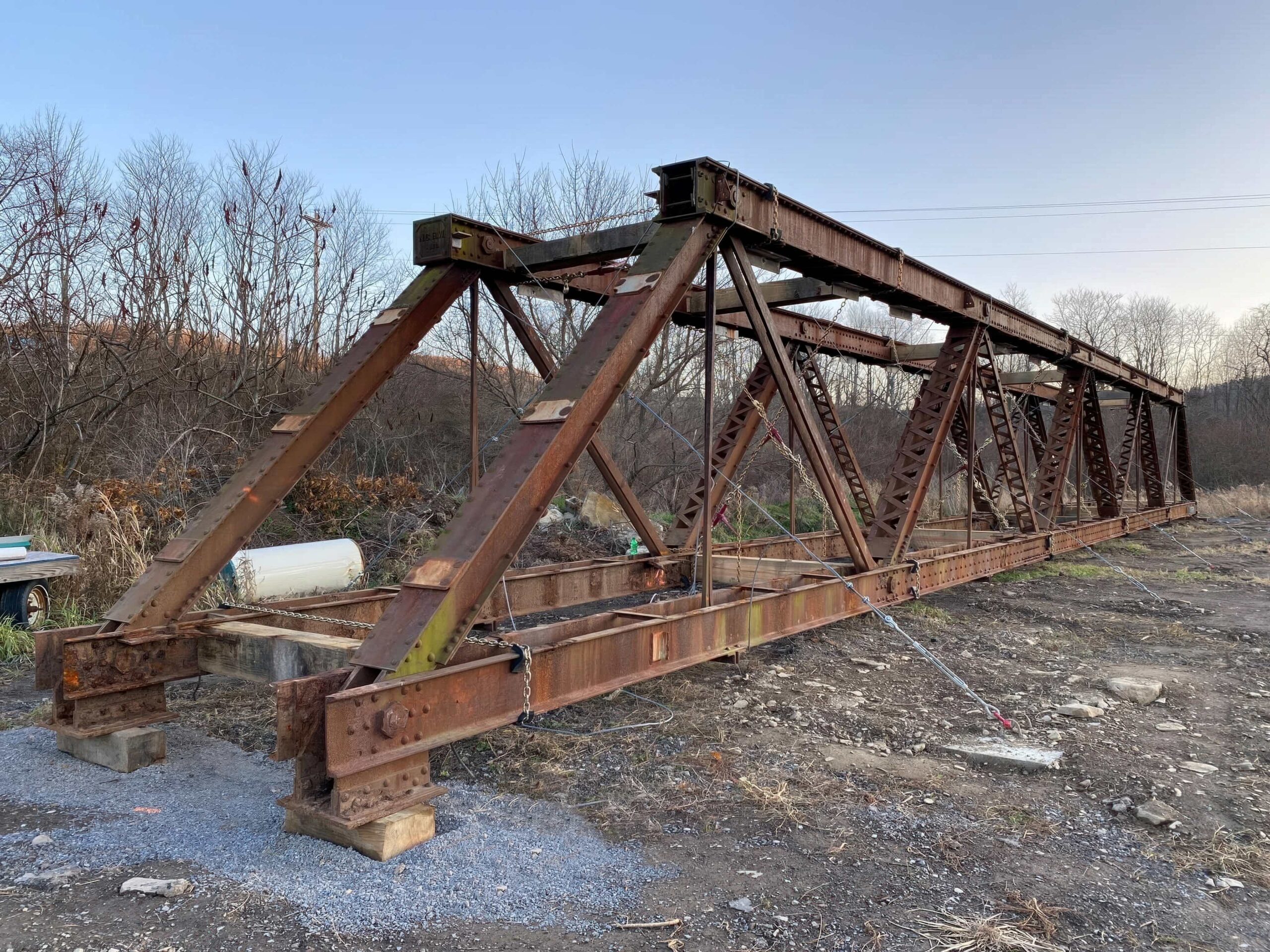 Rusty metal bridge on the ground with cables.