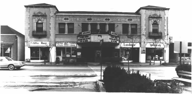 Black and white photograph of large building with many large windows and two square towers at either end.