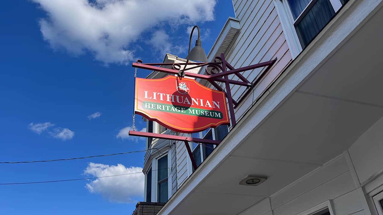 Red, white, and green wooden sign on a building.