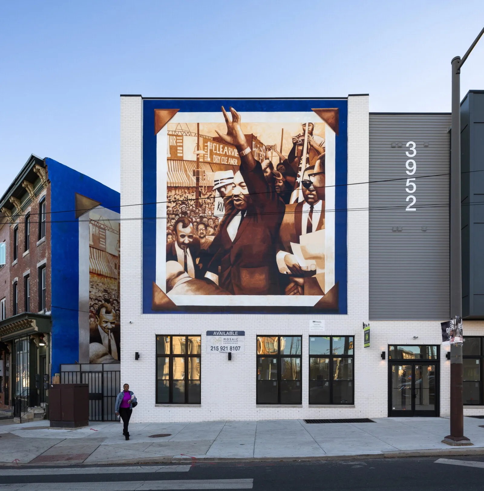 Colorful mural on a tall white building on an urban block.